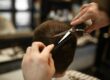 a person cutting another persons hair with a pair of scissors