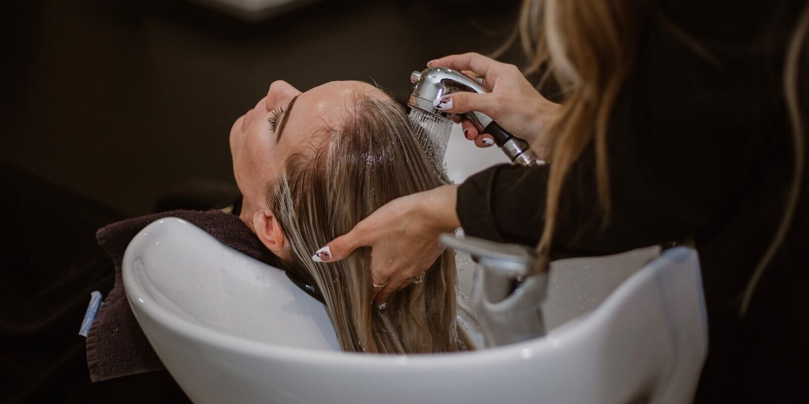 a woman getting her hair cut by a hair stylist