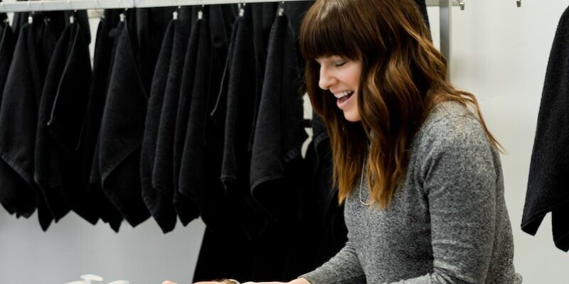 woman in gray sweater holding white clothes hanger